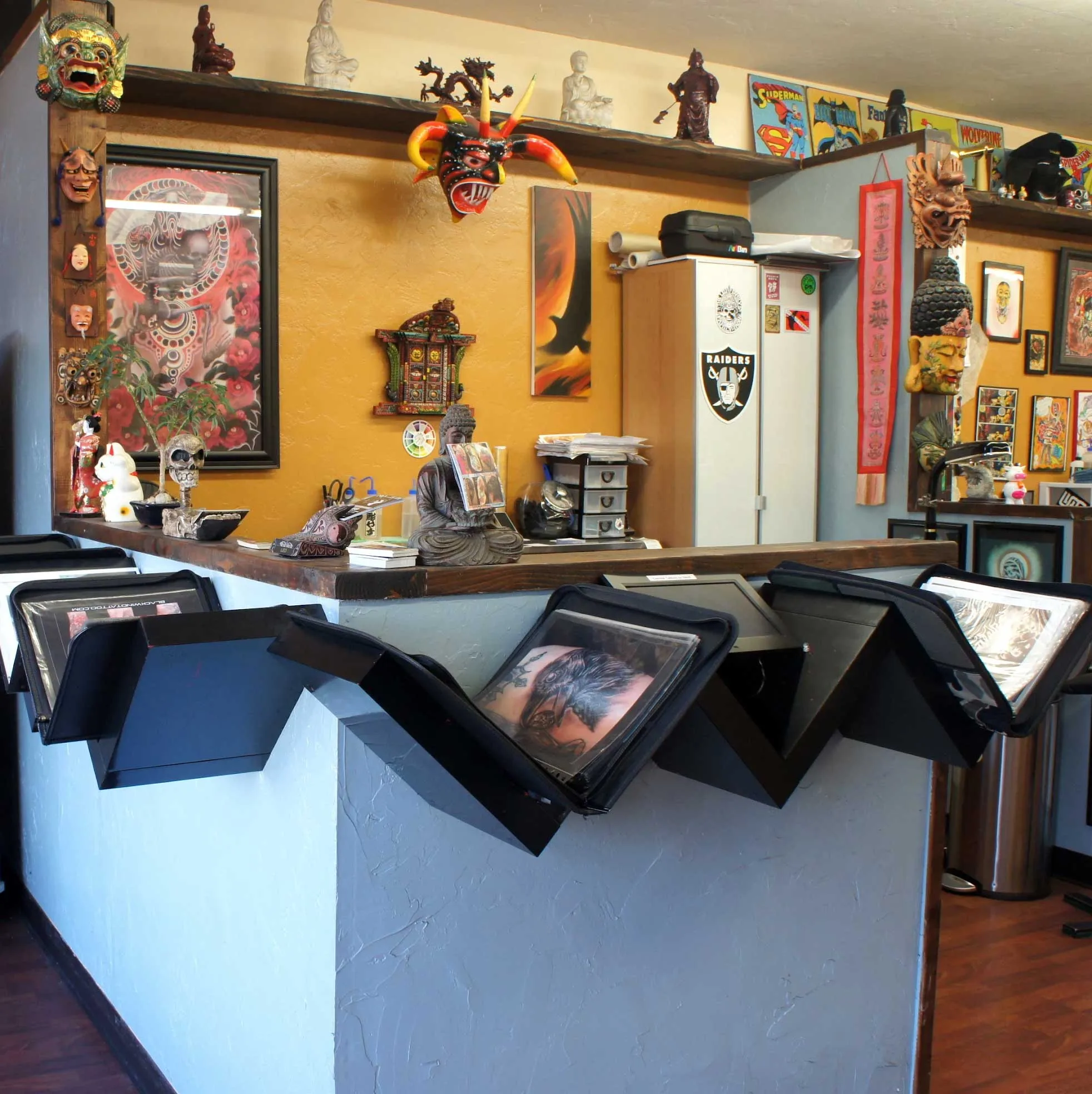 Inside Funhouse Tattoo — front desk with portfolio books and eclectic art